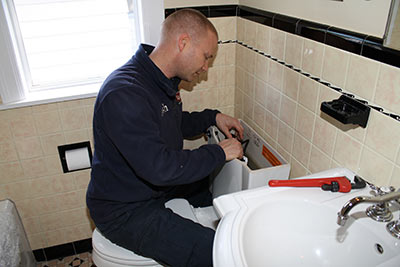 Hank is working on fixing a broken toilet